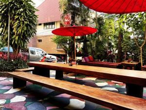 a wooden bench with a red umbrella on a patio at Panda House Chiang Mai in Chiang Mai