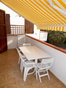 a white table and chairs on a balcony with a table and a yellow curtain at Trilocale con A/C a Marcelli - M035 in Marcelli