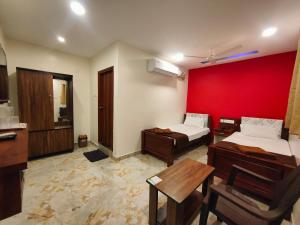 Habitación con 2 camas y pared roja. en Crown Hotel en Tiruvannāmalai