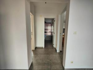 un pasillo vacío con paredes blancas y suelo de baldosa en Apartament spațios en Bragadiru