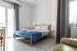 a bedroom with a bed with a blue blanket at V-rooms in Milos Cyclades in Pollonia