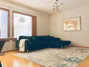 a living room with a green couch and a rug at Detached house Mämmensalmi in Äänekoski