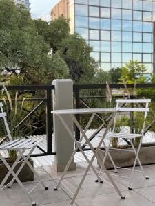 ein weißer Tisch und zwei Stühle auf einem Balkon in der Unterkunft Departamento VIGGO in Mendoza + 40 Fotos