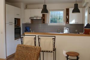 a kitchen with white cabinets and a counter with two chairs at esterel-plage in Saint-Raphaël