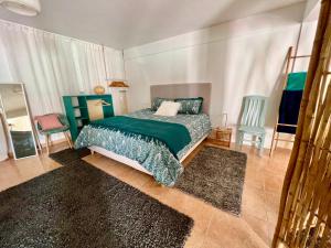 a bedroom with a bed with a green comforter and two chairs at Nazare Oasis Suites and Retreats in Nazaré