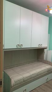 una cocina con armarios blancos y un banco en una habitación en Casa Alessio, en Cesano Maderno