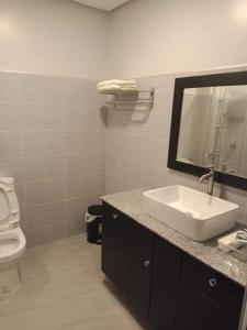 a bathroom with a sink and a toilet and a mirror at Samal Sands and Shores in Magamomo