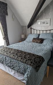 a bedroom with a large bed with a blue comforter at The Carmen Guesthouse in Llandudno