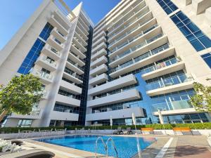 an apartment complex with a swimming pool and two tall buildings at Comfy Azizi Aura Studio in Dubai