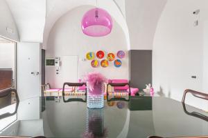 um quarto com uma mesa de vidro e um pendente cor-de-rosa em Carraio Salentino by BarbarHouse em Parabita
