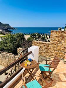 Un patio con mesa y sillas y el mar. en Argentiera HollyHouse, en Miniera dellʼArgentiera