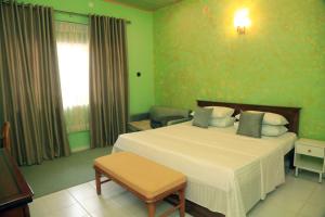 ein Schlafzimmer mit einem großen weißen Bett und einem Sofa in der Unterkunft Palm Grove in Colombo