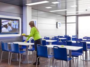 a woman standing in a room with tables and chairs at Ibis Budget Madrid Vallecas in Madrid