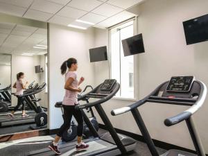 a woman running on a treadmill in a gym at Ibis One Central - World Trade Centre Dubai in Dubai