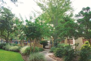 a garden with trees and plants and a sidewalk at La Quinta by Wyndham Houston Bush IAH South in Houston