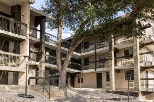 een appartementencomplex met bomen ervoor bij La Quinta Inn by Wyndham San Antonio I-35 N at Toepperwein in San Antonio