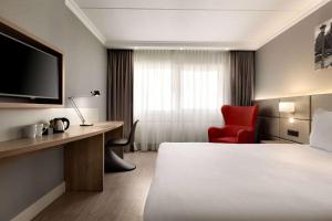 バドフーフェドルプにあるRamada by Wyndham Amsterdam Airport Schipholのベッドと赤い椅子が備わるホテルルームです。