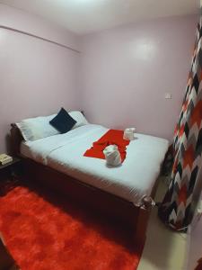 JAYDE COSSY HOMES في ناكورو: غرفة نوم بسرير وبطانية حمراء