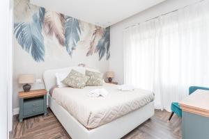 a bedroom with a white bed with a tropical painting on the wall at Gregory 7House Vaticano in Rome