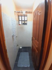 a small bathroom with a shower and a door at JAYDE COSSY HOMES in Nakuru