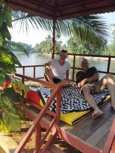 two men are sitting on a bed on a boat at The Lake Paradise Boutique Resort in Alleppey