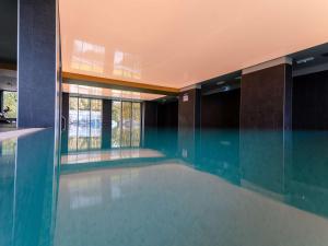 a swimming pool in a building with glass walls at Mercure Sibiu Arsenal in Sibiu