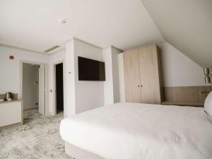 a white bedroom with a white bed and a tv at Mercure Sibiu Arsenal in Sibiu