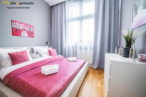 um quarto com uma cama rosa com duas toalhas em Baltic Apartments - Wisus em Świnoujście