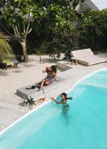 2 kleine Mädchen spielen im Schwimmbad in der Unterkunft Seconda Stella in Jambiani