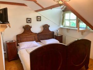 Un dormitorio con una gran cama de madera con sábanas blancas. en etno kuća Đeram en Mokrin