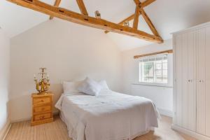 een witte slaapkamer met een bed en een raam bij The Little House in Thatcham