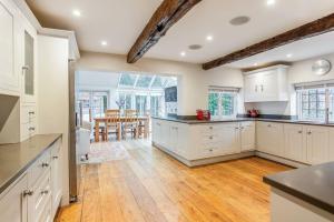 cocina con armarios blancos y suelo de madera en The Little House en Thatcham