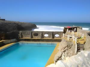 a swimming pool with the ocean in the background at Habitaciones con vistas a playa Do Guincho in Cascais