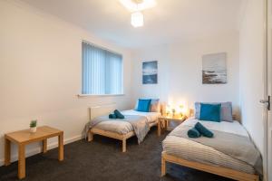 two beds in a room with blue pillows at 2Bed-Free Parking-EV Charger in Wishaw