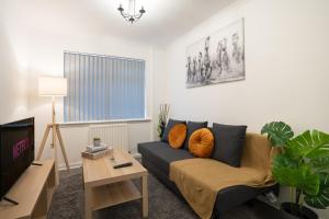 a living room with a couch and a tv at 2Bed-Free Parking-EV Charger in Wishaw