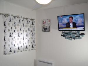 a television hanging on a wall in a room at Appartement T2, Climatisé, 3 étoiles, 40m2 ,parking privé, Mer 300m, Wifi, Piscines, très propre, Ascenseurs, en étage in Le Grau-du-Roi