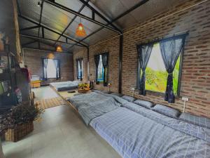 a bedroom with two beds and a brick wall at Vườn Trên Mây - Skyline Farm & Homestay in Mộc Châu