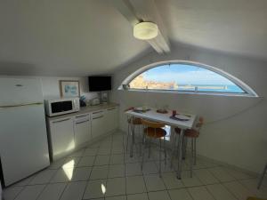コリウールにある3CONV48- Charmant T2 avec vue imprenable en face plage Collioureの窓付きのキッチン、テーブルと椅子
