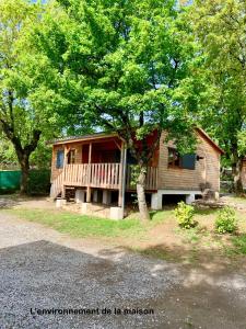 Cabaña de madera con porche y árbol en Camping les Chênes, en Chauzon