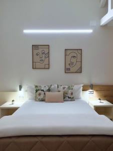 ein Schlafzimmer mit einem großen weißen Bett mit drei Bildern an der Wand in der Unterkunft Simona Apartments in Portocannone