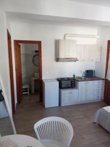 a kitchen with white cabinets and a table and chairs at kominoshouses in Skala