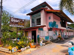 een roze gebouw met schilderijen aan de zijkant bij Ingpha Room For Rent in Satun