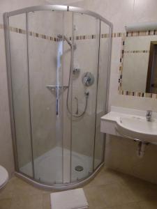a shower with a glass door next to a sink at Pension Lahn in Rablà