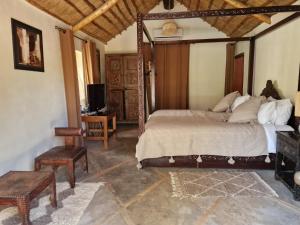 a bedroom with a bed and a desk and a television at Manzal Lahbab, 2Villas 2Bungalows 2Piscines et Jardins in Marrakech