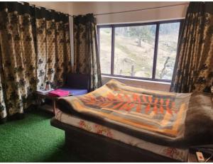 a room with a bed and a window with a laptop at Hotel Grand Abdullah, Pahalgam in Pahalgām