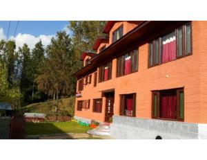 a large orange building with red doors and windows at Hotel Grand Abdullah, Pahalgam in Pahalgām