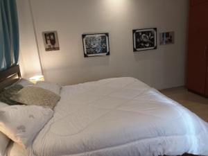 uma cama branca num quarto com fotografias na parede em ADB Properties em Ogbojo