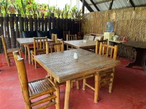un grupo de mesas y sillas de madera en un restaurante en Villa Gumamela Siargao, en Catangnan