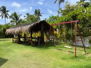 un parque infantil con una cabaña y un columpio en Villa Gumamela Siargao, en Catangnan