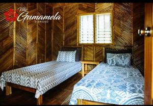 2 camas en una habitación con paredes de madera en Villa Gumamela Siargao, en Catangnan